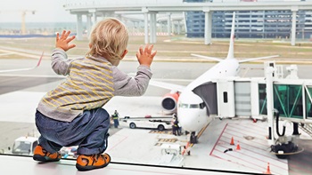 Bimbo in aeroporto guarda l'aereo fuori dal vetro